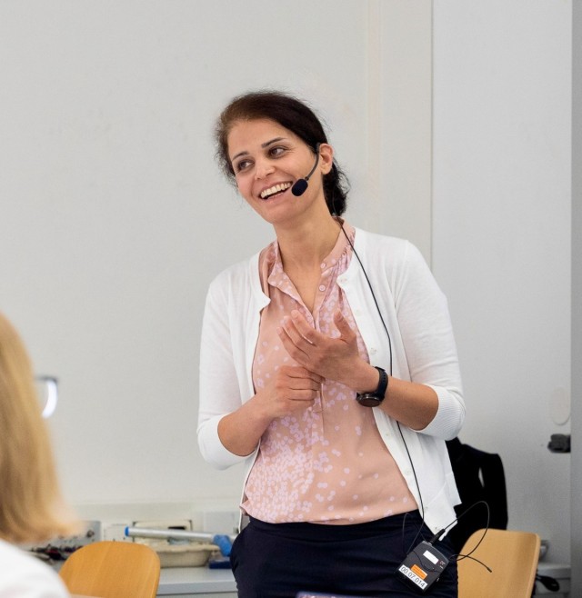 Layla Hormozi stands at the front of the classroom while giving a talk, laughing.