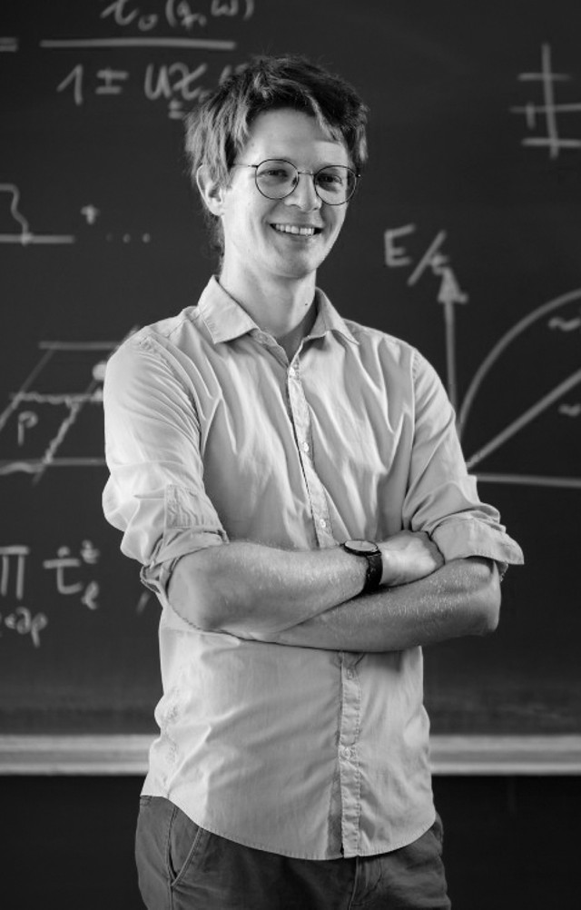 Fabian Grusdt standing in front of a blackboard filled with formulas.