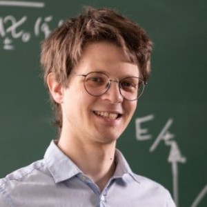 Fabian Grusdt standing in front of a blackboard filled with formulas.