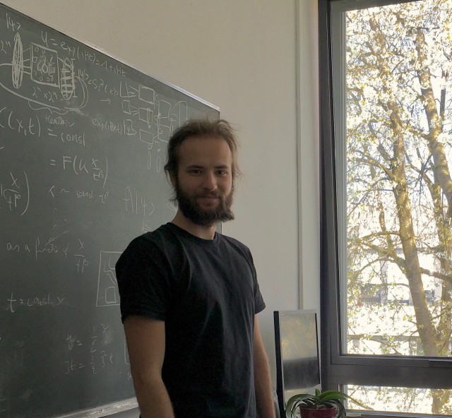 Alex Schuckert standing in front of a blackboard. 