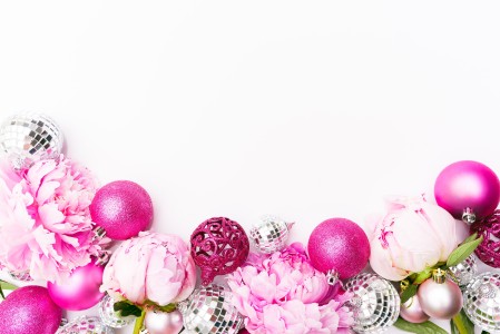 Pink Christmas baubles and pink peonies on a white background. 