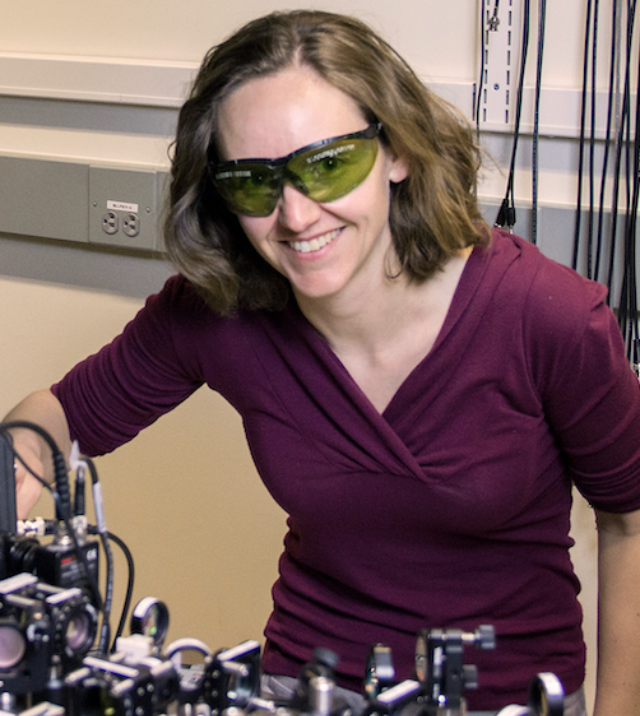 Cindy Regal with laser protection glasses bending over an experiement