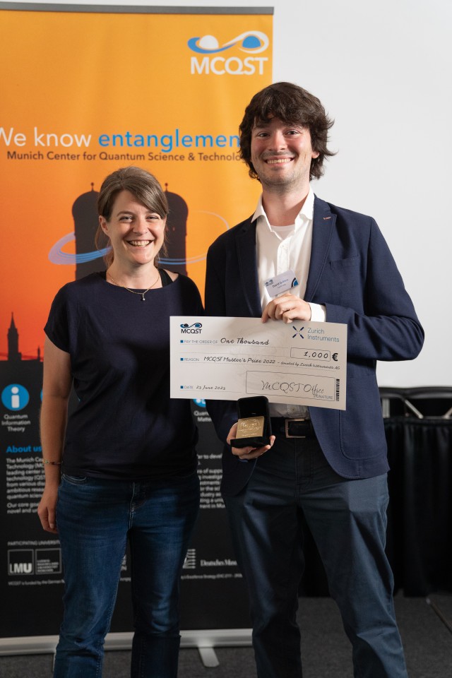 Thesis supervisor and student standing alongside each other showcasing the holding the award check at the MCQST2023 conference.