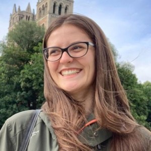 Female Phd Student smilling, standing on the Isar river bank.