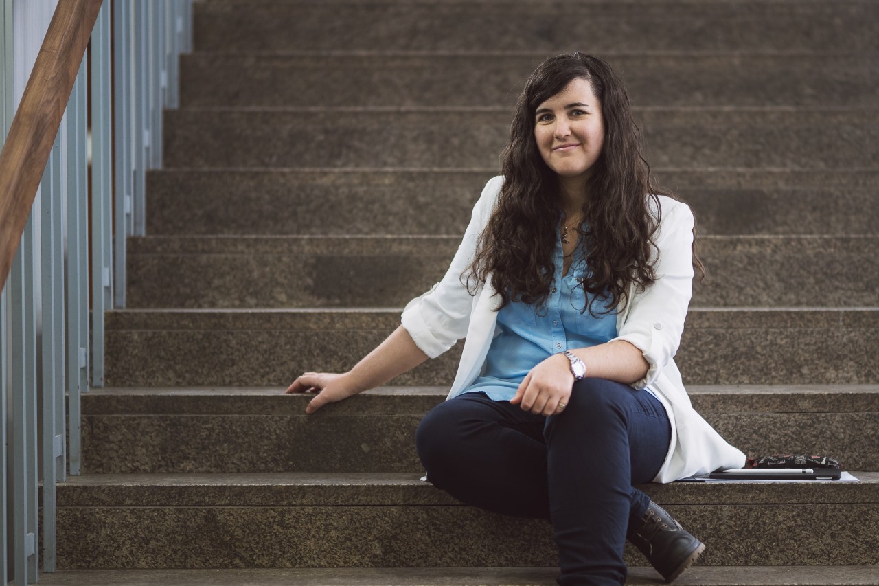 Ángela Capel siiting on the stairs of the LMU Physics foyer. 