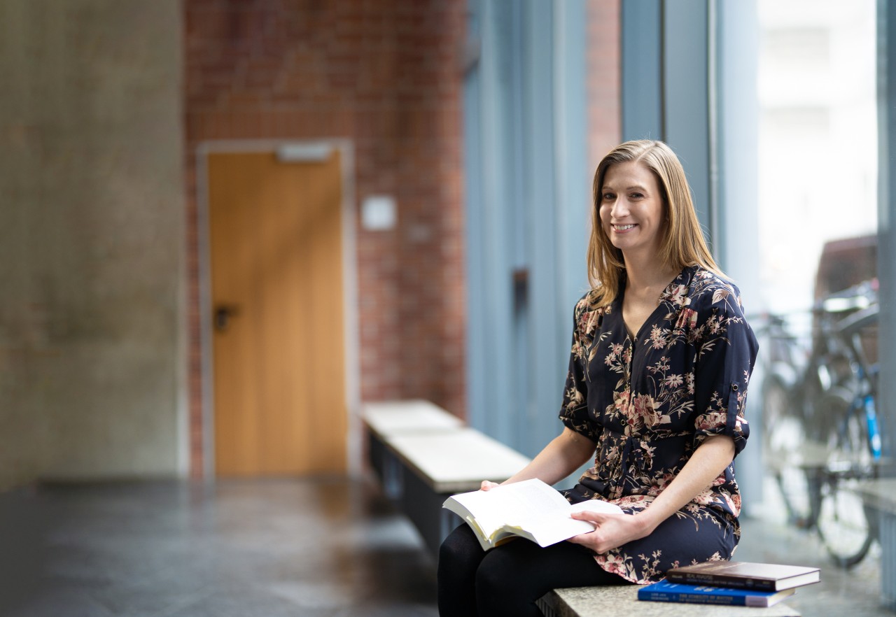 Amanda Young sitting on a window bench inside the LMU Physics builduing. 