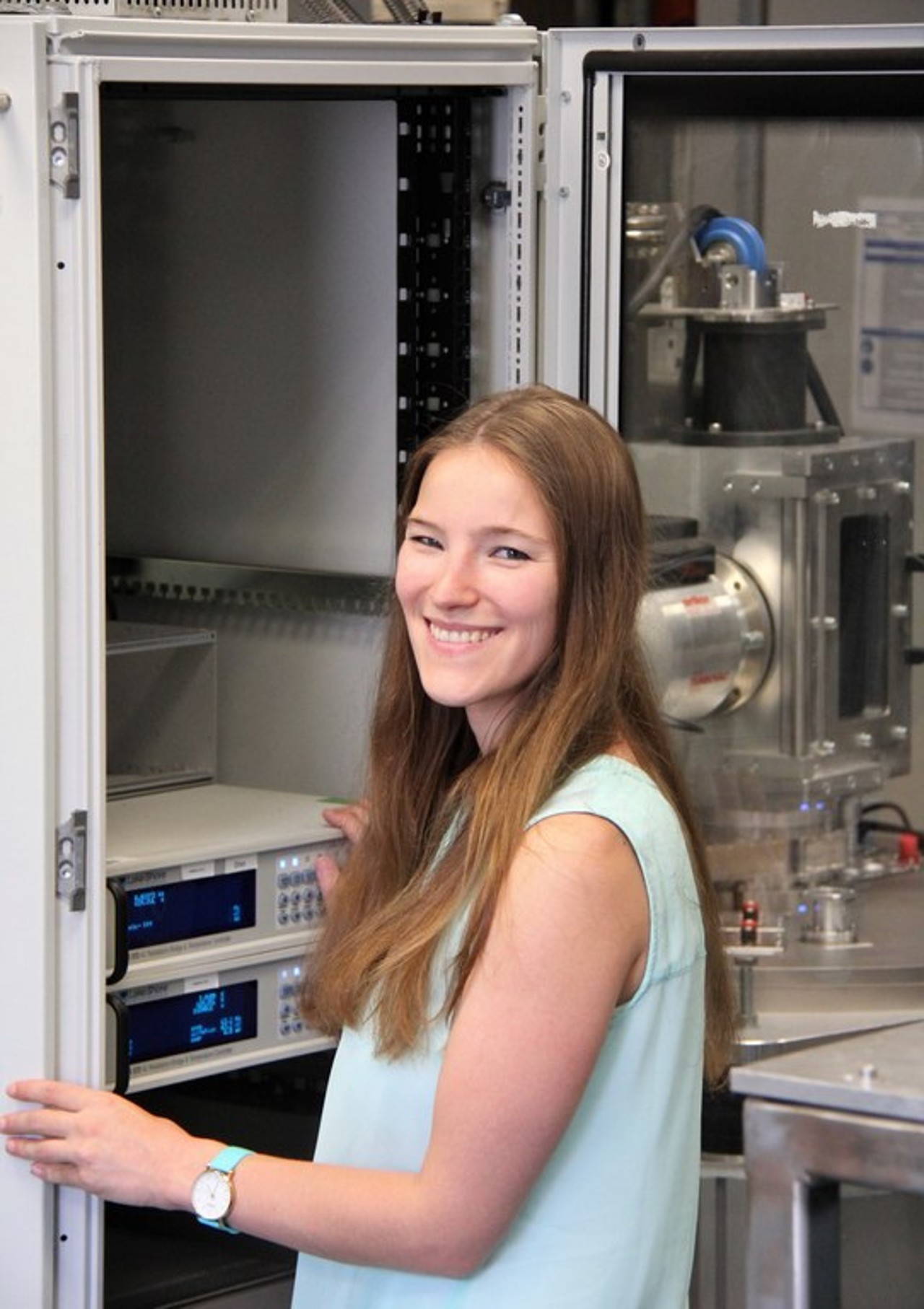 Carolina Burger standing in her lab in front of measuring devices.