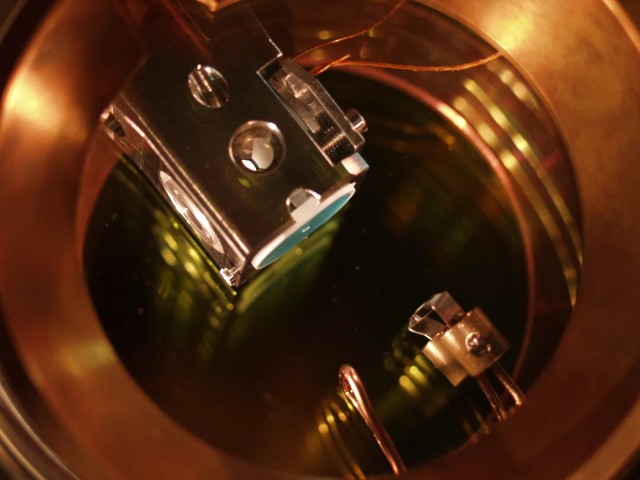 Close-up of an optical resonator in a vacuum. A single rubidium atom is trapped between the conically shaped mirrors inside the holder.