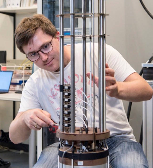 Andreas Wendl sitting and working on a superconducting magnet system in the lab.