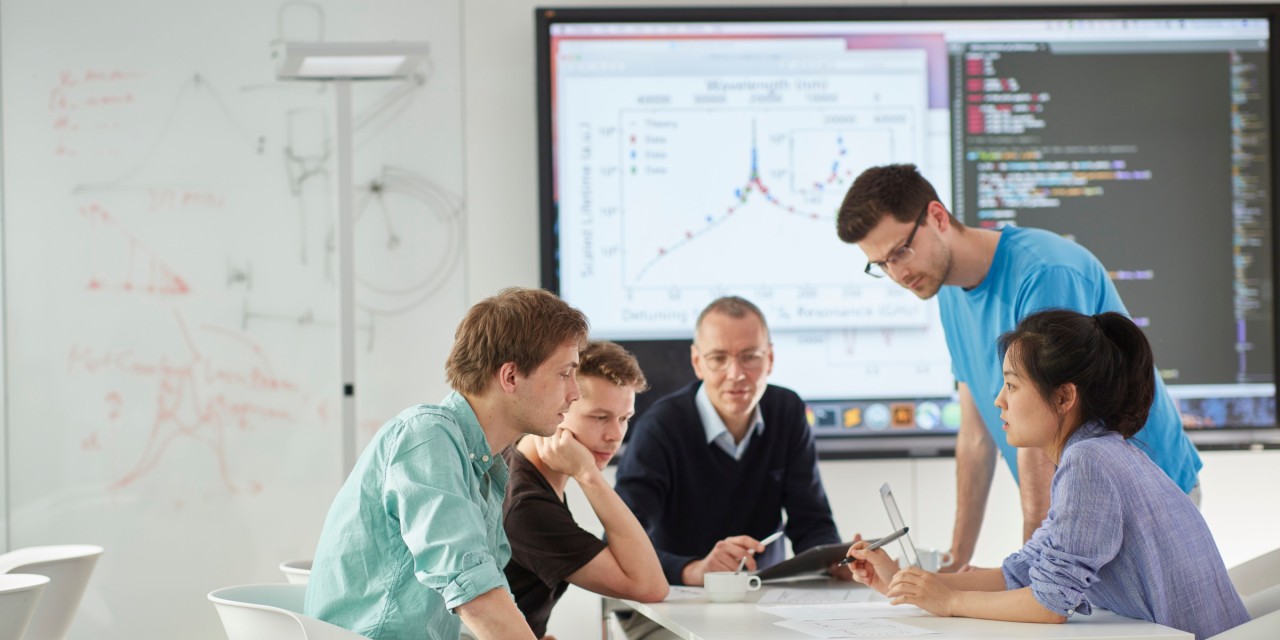 Group of people around a table discussing and working together.