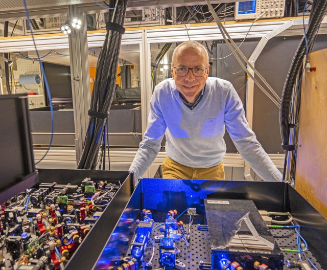 Immanuel Bloch leaning forward over an optical table in his lab. 