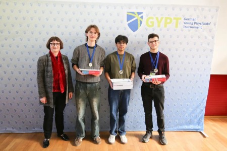 The silver medal winners Ayush Yadav, Mihailo Macesic, and Nikita Petrov with the designated president of the German Physical Society, Heike Riel.