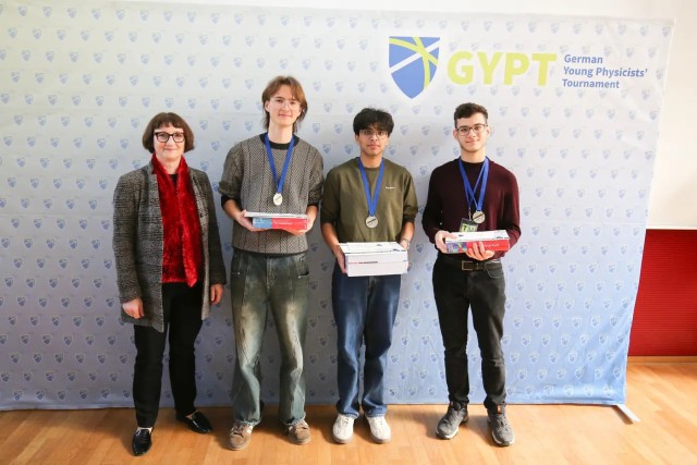 The silver medal winners Ayush Yadav, Mihailo Macesic, and Nikita Petrov with the designated president of the German Physical Society, Heike Riel.