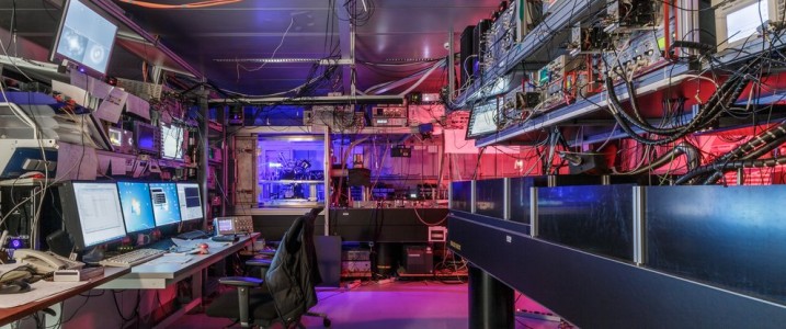 Experimental physics laboratory with computers and top tables featuring red and purple lights. 