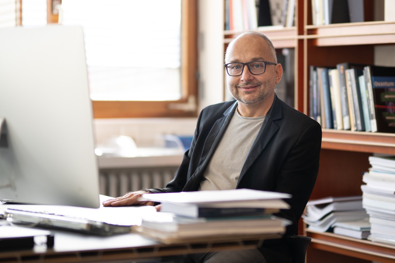 Prof. Ulrich Schollwöck sitting at his desk in his office. 