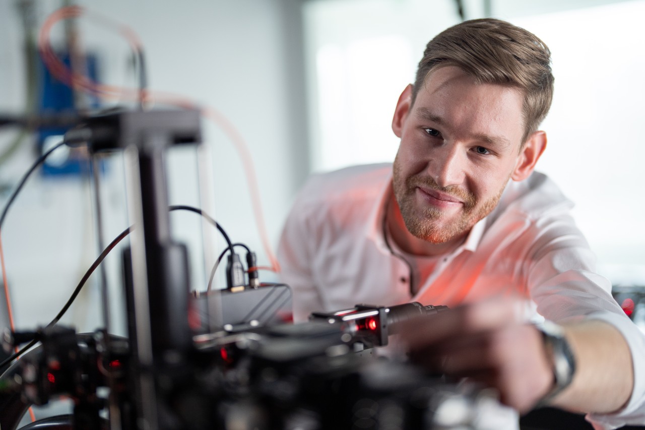 Male researcher adjusting a laser set-up in a laboratory.