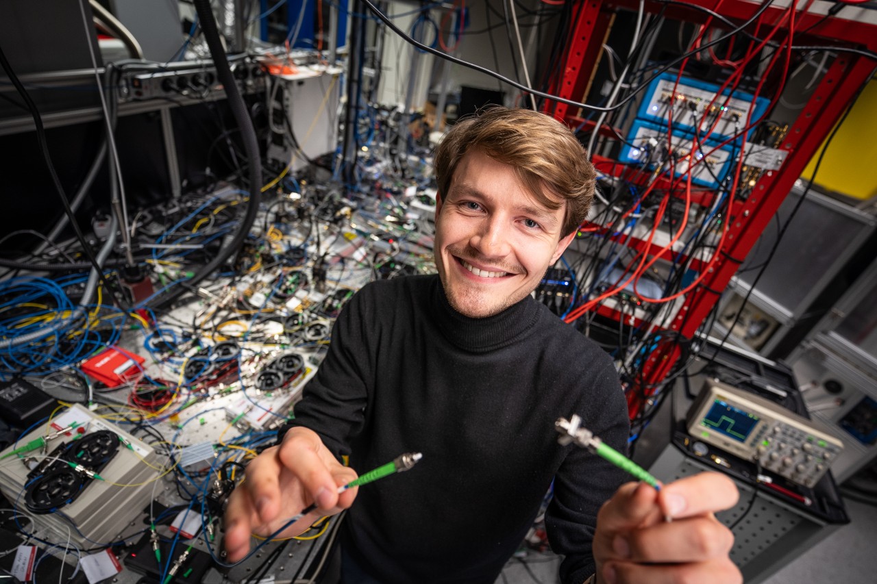 Male researcher connecting two cables before the camera, in his laboratory.