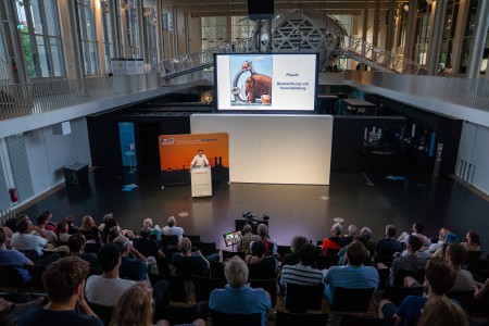 Markus Aspelmeyer giving a public talk at the Deutsches Museum in front of a full auditorium.